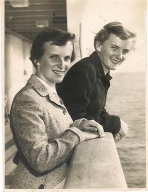 Two women smiling on a ship deck, leaning on the rail — Bobbie and Jill Webber on the Arcadia, 1954