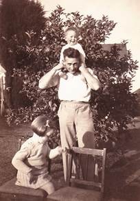 Len, Barbara and Roderick Rowe at 4 Atkins Ave, Glen Iris — outdoor snapshot, Len Rowe holding baby Roderick on his shoulders/head, laughing, Barbara standing beside him