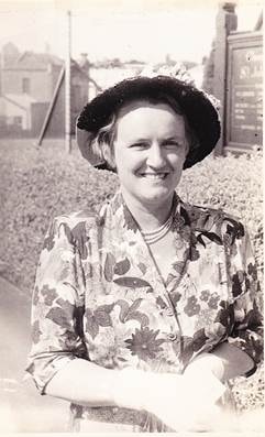 Lil Webber Rowe in floral dress and dark hat with net veil, smiling outdoors, c.1940s