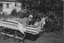 Lil Rowe leaning over a pram/perambulator in a garden, c.1940s