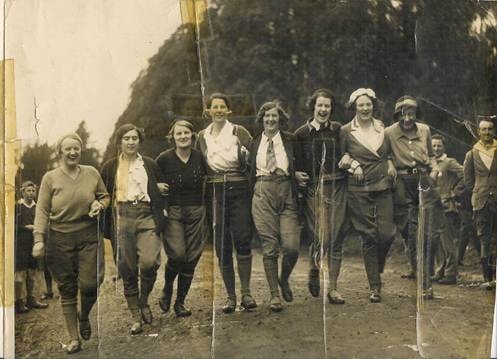 Large outdoor hiking group photo — people walking in line along bush/country path, 1930s hiking clothes