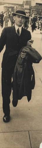 Robertson family man in suit and hat walking on a city street, carrying a coat — c.1930s