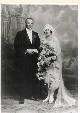Formal wedding portrait: bride in lace gown with long veil and large bouquet of flowers, groom in morning suit — Robertson–Strange wedding, c.1920s