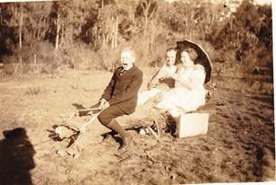 Three Robertson/Webber family members on a farm vehicle or cart in a paddock — bush behind, c.1920s–1930s