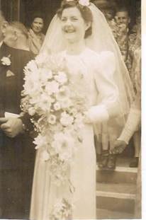 Eileen Webber — outdoor wedding photo, Eileen Mann/Webber (bride, white gown, long veil, large cascading bouquet), standing alone on church steps