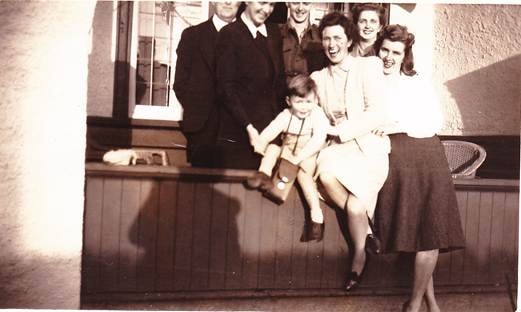 Group of people on a pub or hotel verandah, c.1940s–1950s — informal gathering, men and women standing and seated on a timber verandah