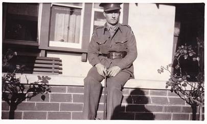Robertson/Webber family man in Australian WWII military uniform sitting on a brick fence outside a house, c.1940s