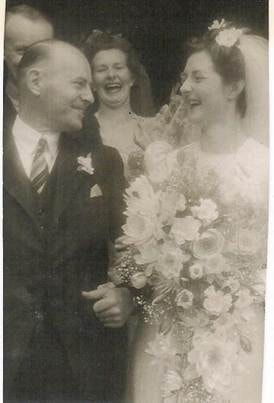Robertson/Webber family wedding — older man with bride holding large bouquet, woman laughing behind, outside church, c.1940s