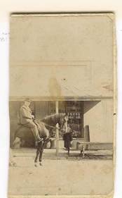 Benjamin Arthur (Acker) Webber on his horse Myrtle outside the hotel and store, showing M Webber Family Grocer signage